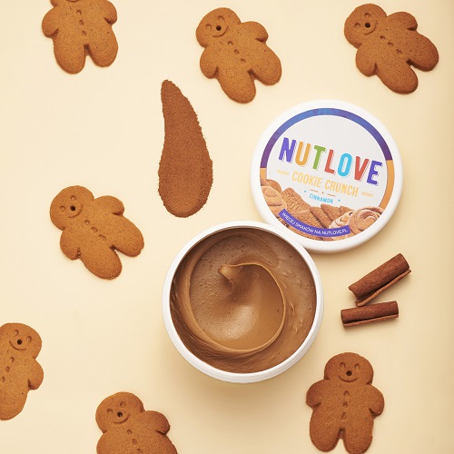 Allnutrition Nutlove Cookie Crunch Cinnamon 500g nut butter spread with visible cinnamon sticks and gingerbread cookies, creamy texture, top view, beige background.