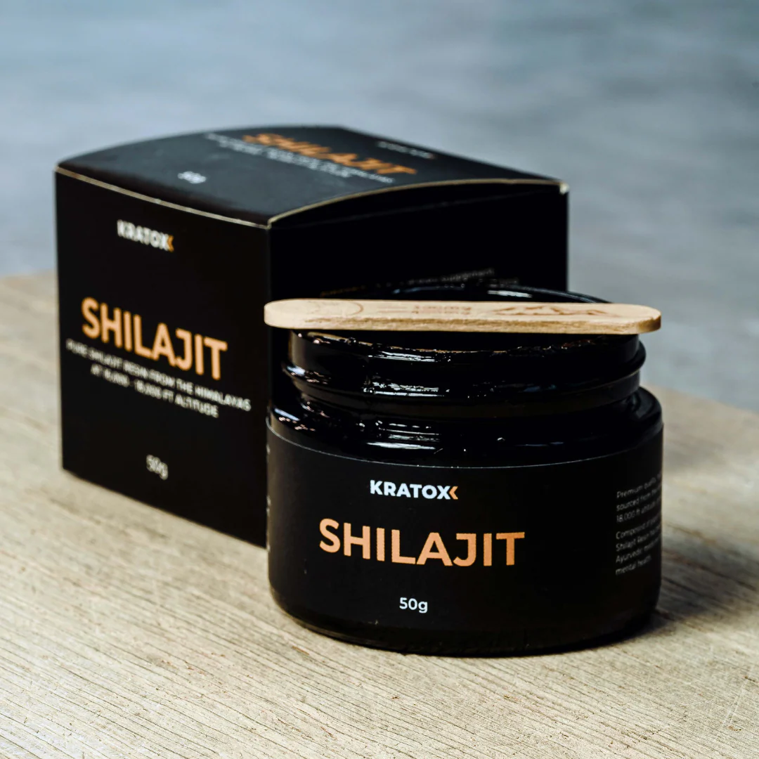 Kratox Shilajit Resin 50g jar with spatula scooping a small amount of dark resin from the container.
